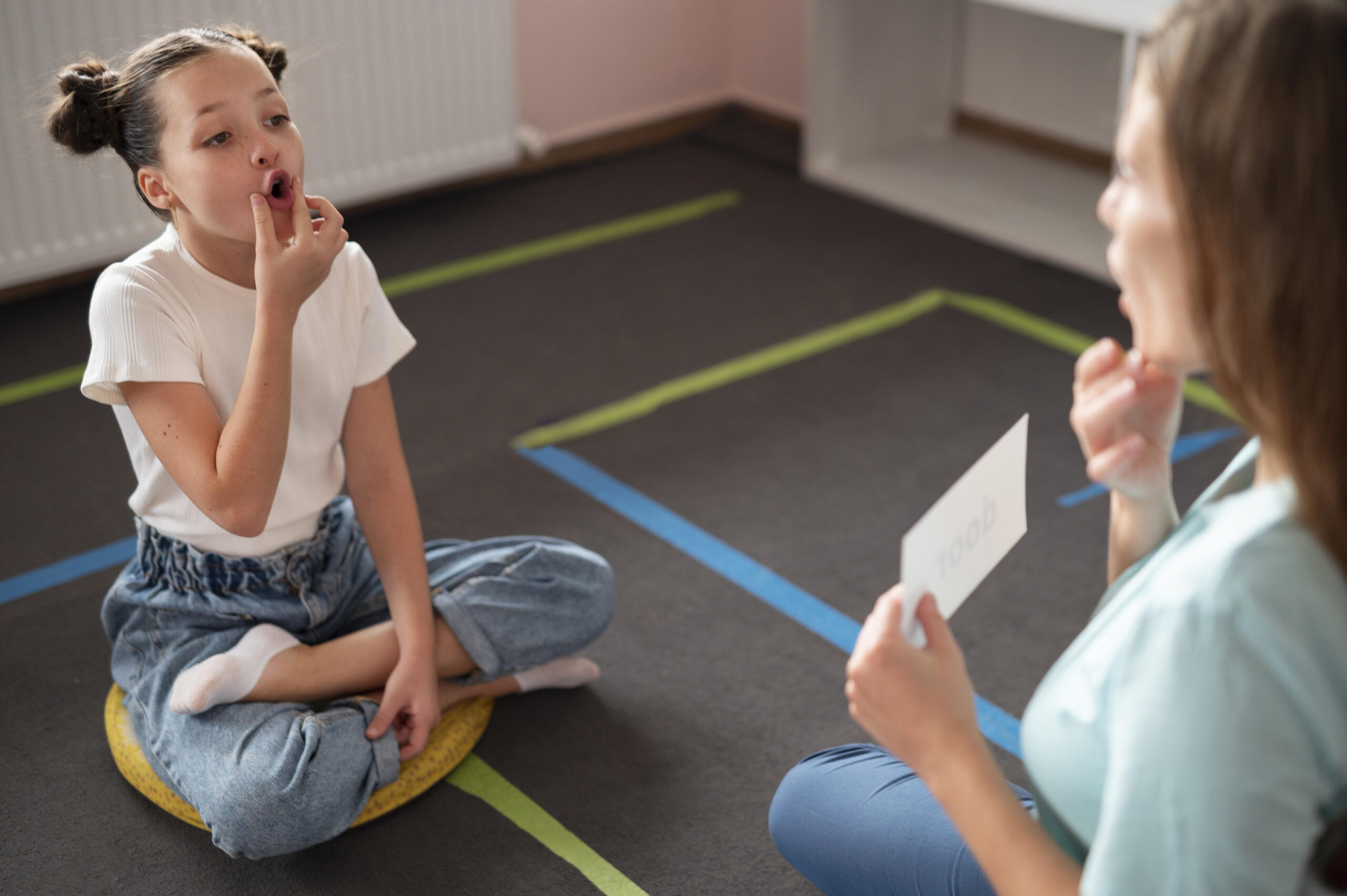 Psicóloga ayudando a una niña a hacer terapia del habla en interiores