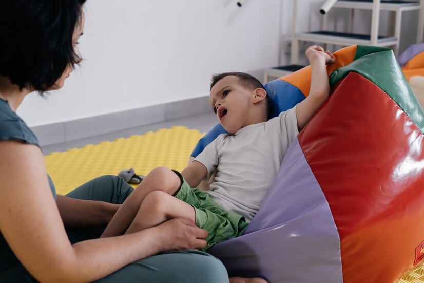 Terapeuta haciendo ejercicios en colchoneta con un niño discapacitado